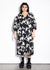 Person wearing a black floral dress against a white background