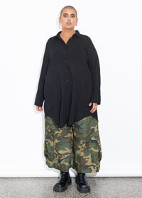 Person wearing a black shirt and camouflage pants on a white background